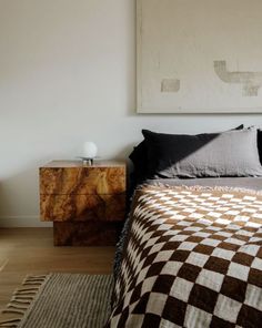 a bed with black and white checkered bedspread in a bedroom next to a painting on the wall