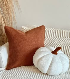 a white pumpkin sitting on top of a couch next to a brown and white pillow