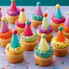 cupcakes decorated with colorful frosting and sprinkles on a table