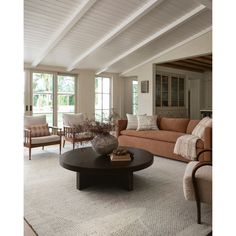 a living room with couches, chairs and a coffee table in front of large windows