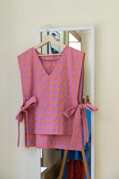 an orange and pink top is hanging on a rack in front of a mirror with clothes