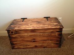 a wooden box sitting on the floor in front of a wall and carpeted floor