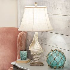 a lamp sitting on top of a table next to a pink chair and a blue vase