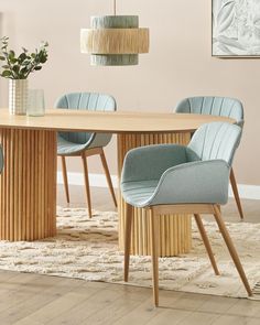 a dining room table with blue chairs and a vase on the floor next to it