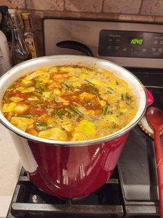 a red pot filled with food sitting on top of a stove