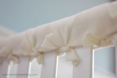 the baby crib is adorned with white ruffles and gold pins on it