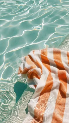 an orange and white towel laying on top of the water