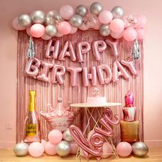 a pink birthday party with balloons and confetti on the wall, including cake