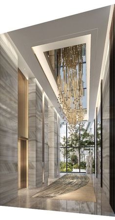 an empty hallway with a chandelier hanging from it's ceiling and large windows