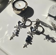 two rings with charms sitting next to each other on a white surface near a candle