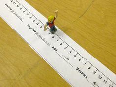 a toy person standing on top of a ruler