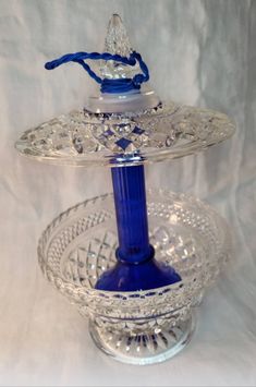 a blue glass candle holder on top of a clear platter with a beaded handle