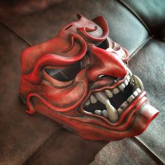 a red mask sitting on top of a leather couch