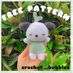 a small crochet koala bear is shown in front of some leaves and bushes