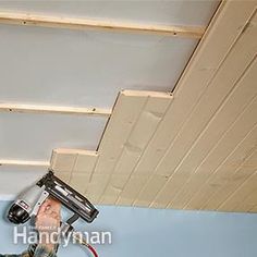 a man is painting the ceiling with a paint roller and an air dryer in his hand