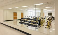 an empty gym with mirrors reflecting the equipment in it's place to work out