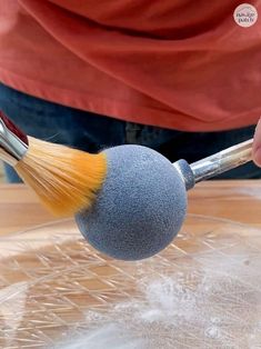 a close up of a person using a brush to paint a ball on a table