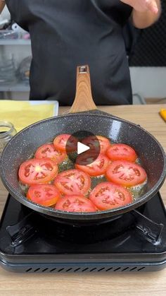 a frying pan filled with sliced tomatoes on top of a stove