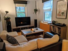 a living room filled with furniture and a flat screen tv sitting on top of a wooden table