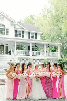 a group of women standing next to each other in front of a white and pink house