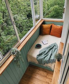 a small window seat in the corner of a room with wood flooring and green walls