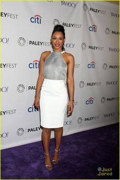 an image of a woman posing on the purple carpet in a white and grey dress