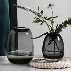 two vases with flowers in them sitting on a table