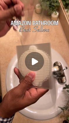 a person is holding a box in front of a sink with the words amazon bathroom best sellers on it