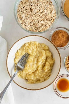 ingredients for oatmeal in bowls on a white counter top with spoons