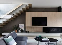 a modern living room with stairs leading up to the upper floor and a television on the wall