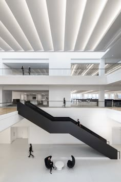 two people walking up and down an escalator in a building with white walls