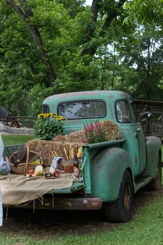 an old truck with hay and vegetables in the bed