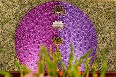 purple and white flowers are growing on the side of a green wall in front of grass