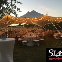 a large tent with tables and chairs set up for an outdoor event at night time