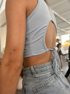 the back of a woman's shirt with a star tattoo on her left arm