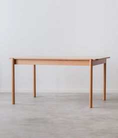 a wooden table sitting on top of a floor next to a white wall and chair