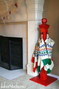 a red fire hydrant sitting in front of a fireplace covered in christmas sweaters