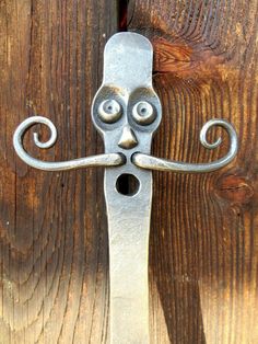 a close up of a metal handle on a wooden door with a face drawn on it