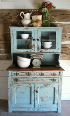 an old dresser has been painted blue and is being used as a hutch for dishes