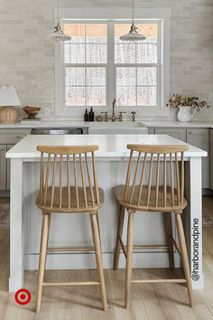 two wooden chairs sitting on top of a white counter in front of a kitchen island