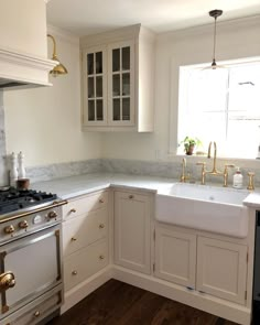 a kitchen with white cabinets and marble counter tops, gold faucets, and an oven