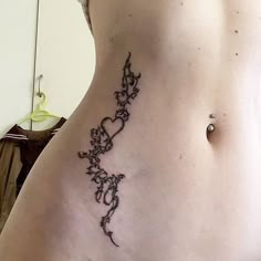 a woman's lower back tattoo with vines and hearts on the side, in black ink