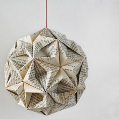 an origami ball hanging from a red string on a white wall with words written all over it