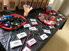 a table topped with lots of items on top of a black cloth covered table next to boxes