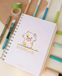 a notebook with an image of a pig on it next to markers and pencils