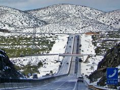 the road is surrounded by snow and mountains