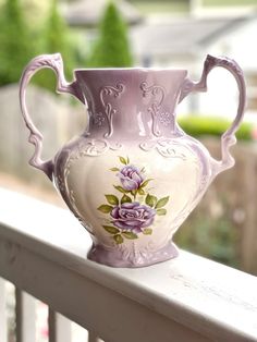 a pink vase sitting on top of a white fence