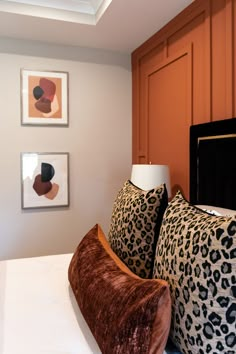 two leopard print pillows sit on a bed in front of framed pictures and art work