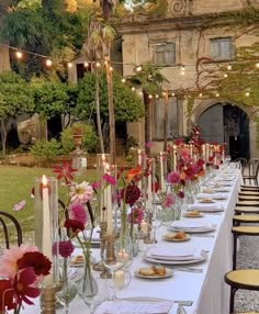 a long table is set up with flowers and candles for an outdoor dinner in the garden