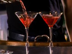 two martini glasses with red liquid being poured into them